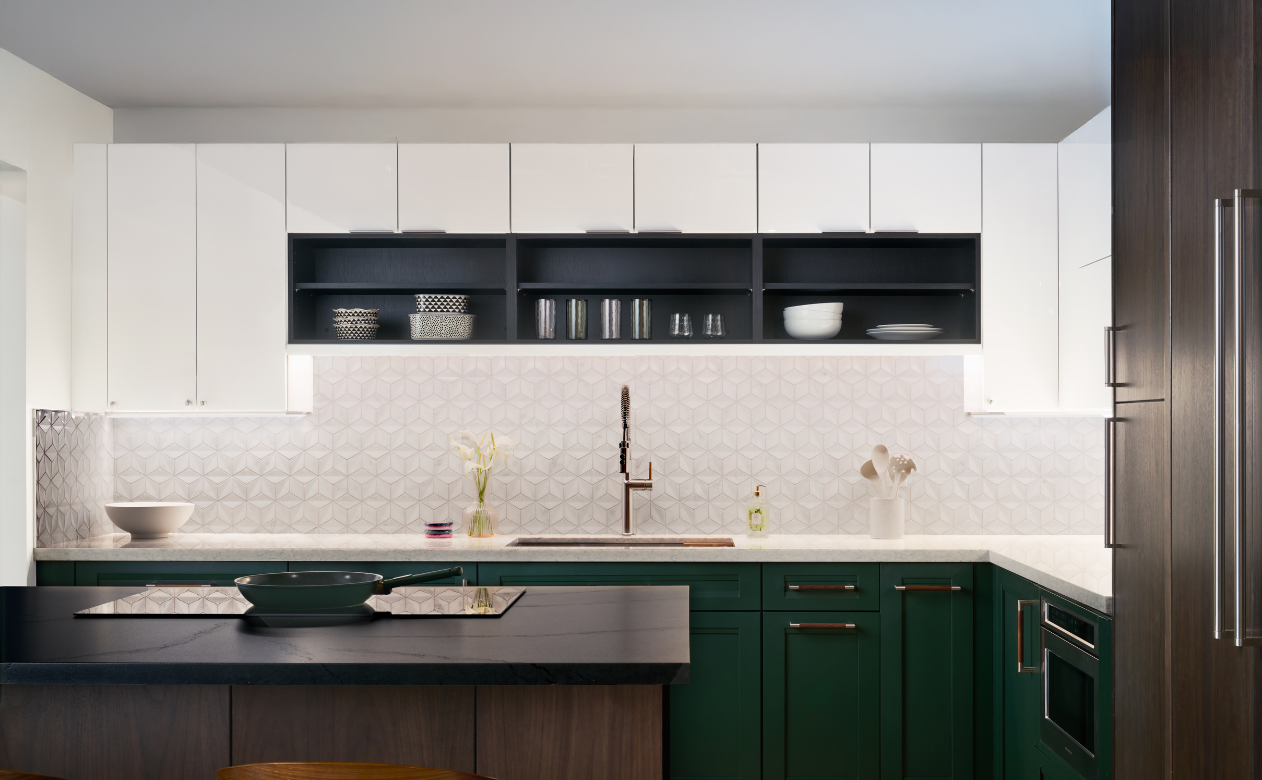 A modern kitchen with white upper cabinets, dark green lower cabinets, a geometric backsplash, and a dark wood island.