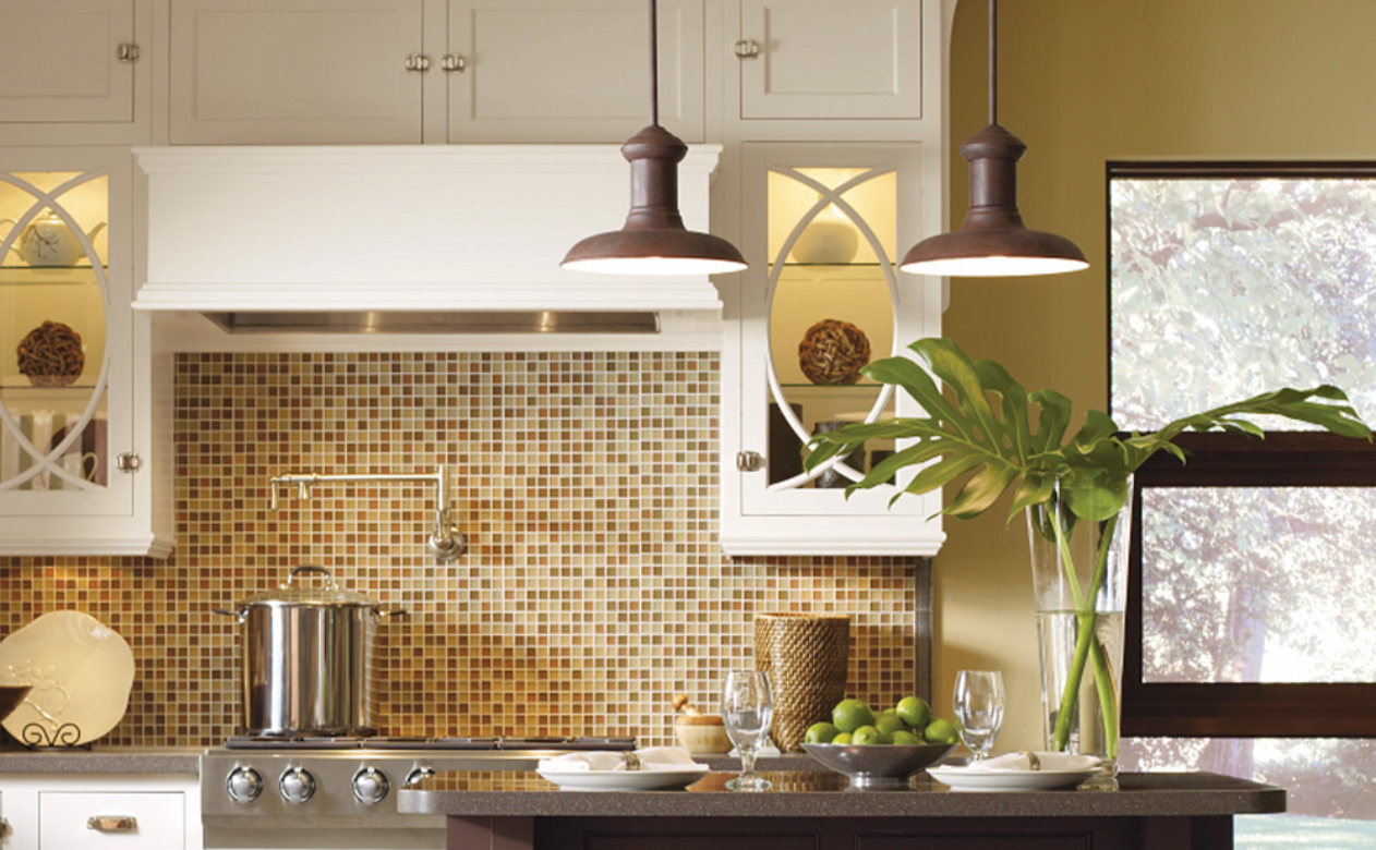 A modern kitchen with white upper cabinets, dark green lower cabinets, a geometric backsplash, and a dark wood island.