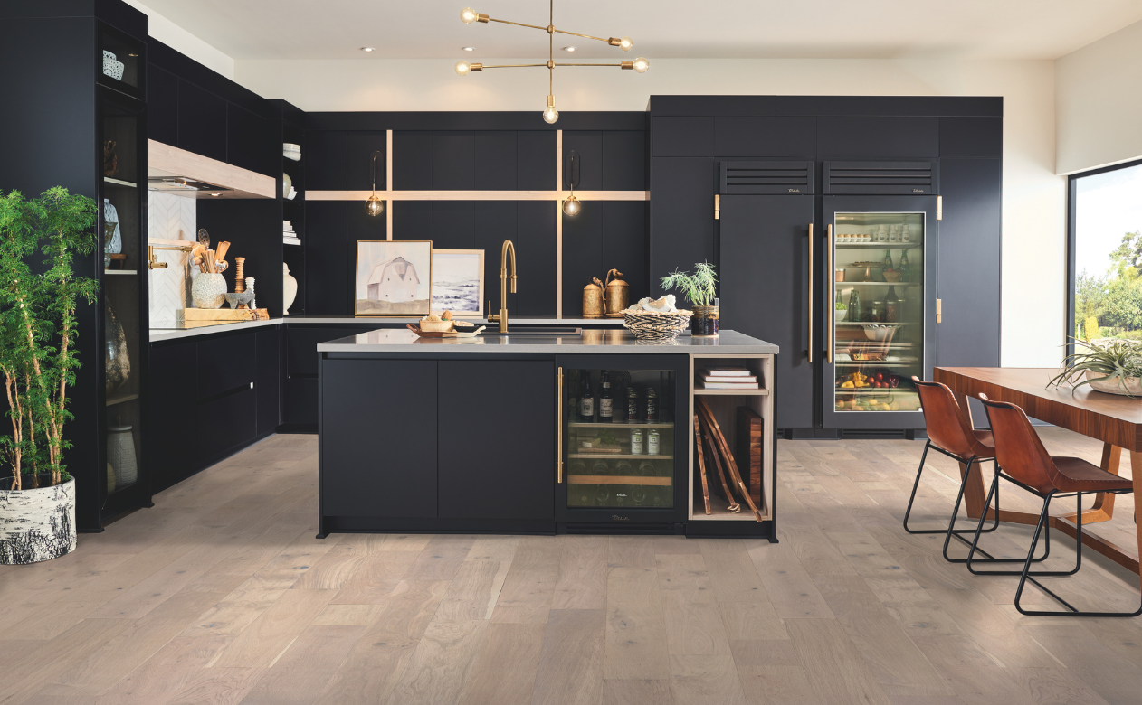 Modern U-shaped kitchen with blue cabinets, white uppers, geometric backsplash, dark wood island, induction cooktop, marble counters, and herringbone wood flooring.